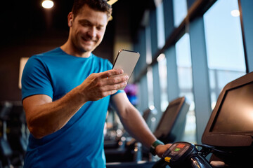 Close up of athletic man using smart phone in health club.