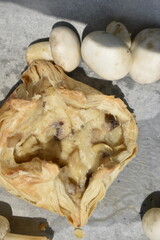 puff pastry with mushrooms decorated by raw champignons, top view