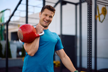 Happy athlete working out with kettlebell in outdoor gym