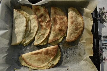 close-up baked burritos and stuffed tortillas on baking sheet, top view 