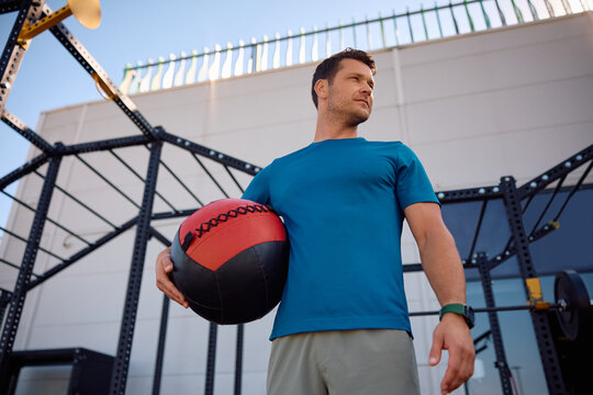Below view of sportsman with medicine ball in outdoor gym.