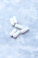 Creatine capsules on bright wooden background. Soft focus. Close up. Copy space.