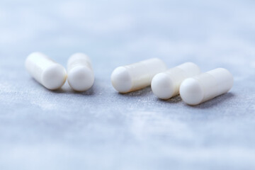 Creatine capsules on bright wooden background. Soft focus. Close up. Copy space.