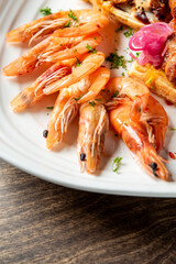 Gourmet seafood breakfast with cooked shrimp, pickled onions, and a savory waffle served on a plate. Close-up shot with vibrant colors and detailed food styling.