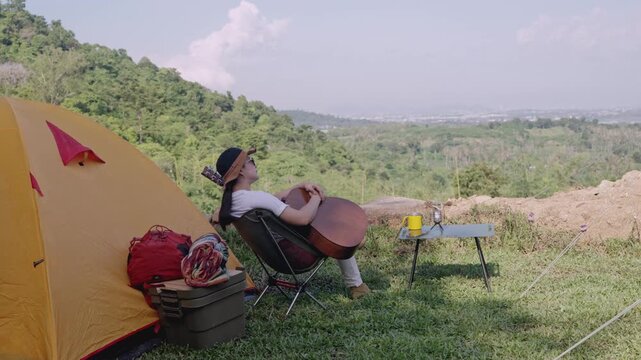 Asian woman camping alone with tent on summer holiday. Outdoor activity and lifestyle.