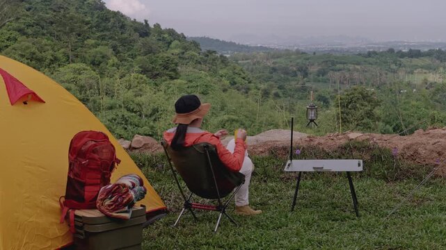 Asian woman camping alone with tent on summer holiday. Outdoor activity and lifestyle.