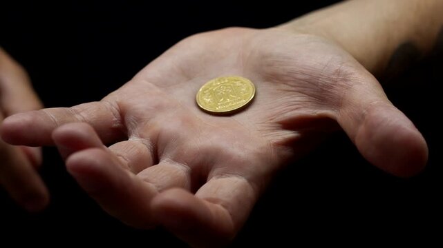 An American cent is in the hands of a guy.
A man holds a metal coin in his hands close-up on a black background.
A man puts a sept. on his hand.
Financial problems and inflation