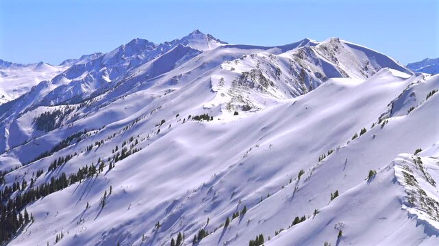 Deep powder snow winter panorama Aspen Highlands Bowl ski resort backcountry high alpine steep terrain Colorado Castle Conundrum Peak Maroon Bells Wilderness Elk Mountain range blue sky sunny static