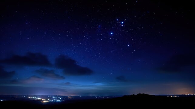 Starry night sky with deep blue hues, stars scattered across the horizon, and subtle distant light
