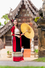 Asian woman in traditional Lanna dress at Wat Intharawat, Chiang Mai. Portrait of young Thai woman...