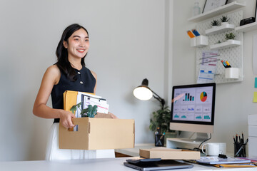 Smiling businesswoman carrying box with personal belongings leaving office after quitting job