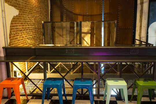 Colorful steel chairs with long wooden table in the old vintage room interior at the cafe restaurant.