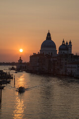 Fototapeta premium A stunning orange sunrise paints the sky above the Ponte dell Accademia, illuminating the Gran Canal and revealing the magic of Venice at dawn