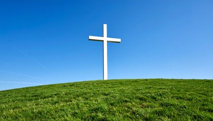 White cross on a grassy hill against a clear blue sky