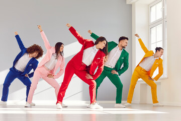 Group of young positive people dancers wearing bright stylish trendy suits dancing together in...