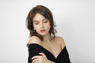 Elegant Woman in Black Off-Shoulder Dress Posing Against White Background 