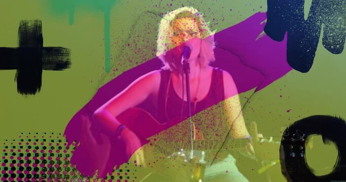 Female singer positioning guitar, strumming chord and activating paint splatter in live set