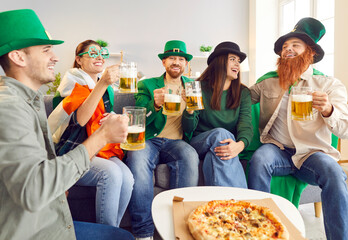 Happy smiling young people friends men and women wearing funny green hats celebrating Saint...