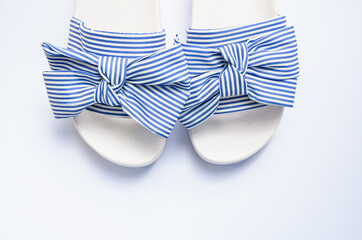 Striped blue and white sandals with bow detail, isolated on white background, top view