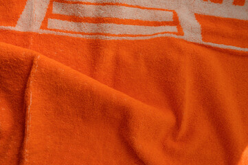 Orange towel on white background, soft bath textile or beach accessory, top view

