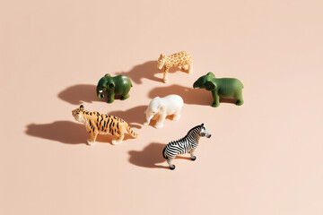 Obraz premium Colorful jungle animal figurines arranged on pastel pink background — playful and minimal flat lay concept for kids