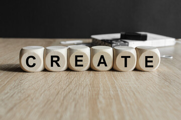 Wooden cubes with the word Create. Beautiful wooden table, black background. Self improvement....