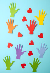 Colorful And Abstract Flat Lay With Paper Hands And Hearts On A Blue Surface