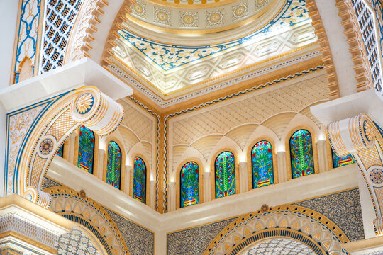 Intricate architectural ceiling with stained glass windows and ornate patterns in beige and blue tones.