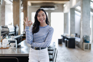Smiling barista gesturing ok sign in coffee shop