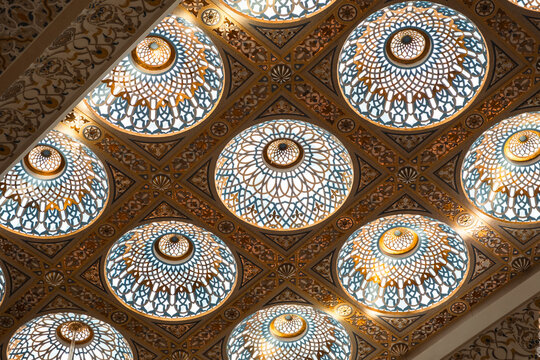 luxurious detailed interior ceiling with intricate geometric patterns and circular stained glass designs, illuminated by light, creating a symmetrical and decorative visual effect. - Powered by Adobe