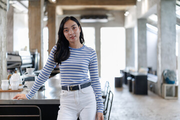 Young asian barista posing in modern coffee shop