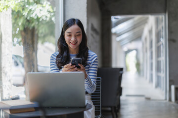 Smiling freelancer using smartphone and laptop in cafe