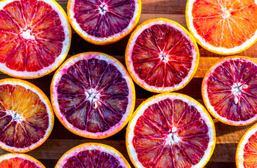Red blood halved oranges close up on a wood background. Top view. Flat lay of fresh orange citrus fruits.
