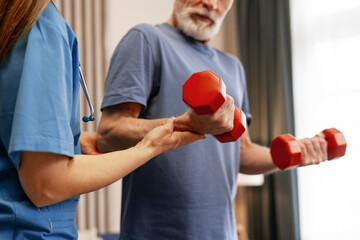 Senior man lifting weights with nurse assistance during rehabilitation exercise