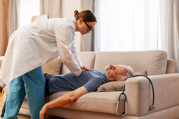 Doctor performing cpr on senior man lying on sofa at home