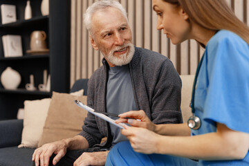 Nurse assisting mature man filling medical form at home