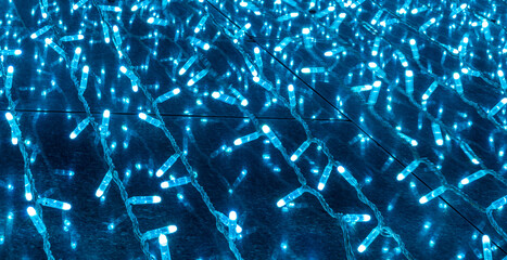 background of holiday colorful blue neon garland for texture and design, festive decoration close up