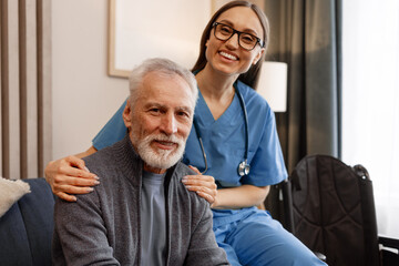 Beautiful woman, female nurse supporting smiling senior man at home or nursing home