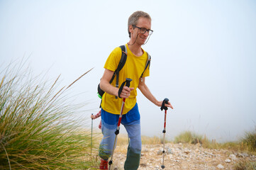 Man Enjoying a Scenic Mountain Hike With Trekking Gear on a Misty Day