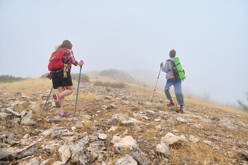 Exploring Foggy Mountain Terrain, Hikers Showcasing Outdoor Enthusiasm and Adventure