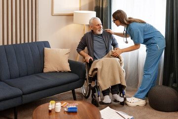 Female doctor, beautiful nurse assisting elderly man in wheelchair at home