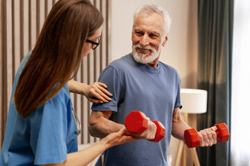 Nurse assisting senior man lifting weights during home visit physiotherapy session