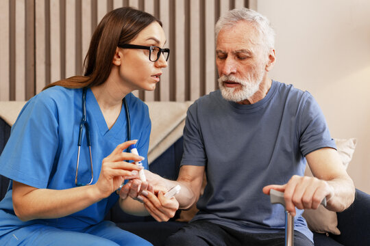 Beautiful nurse assisting elderly man with blood glucose test at home