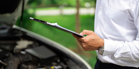 Automotive Inspection. Mechanic reviewing car details with client outdoors.