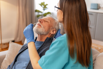 Nurse performing nasal swab test on senior man at home