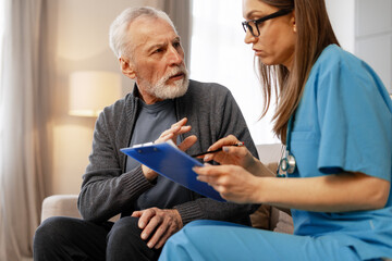 Female doctor explaining medical information to senior patient at home
