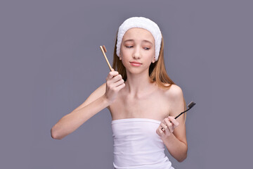 Young caucasian female comparing bamboo and plastic toothbrush for sustainable oral care choices.