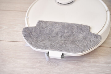 Robotic vacuum cleaner with attached mop on wooden floor for efficient home cleaning.