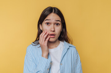 Young woman expresses surprise against a bright yellow background during a casual indoor moment