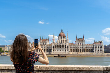 Fototapeta premium Tourist Capturing the Hungarian Parliament on Phone